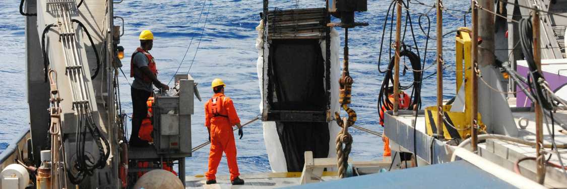 Crew wearing safety gear on a ship deck with VHF radio